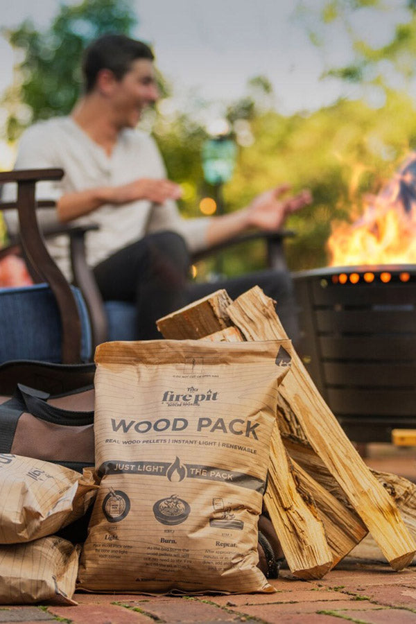 TIKI® Fire Pit Wood Pack and firewood beside a lit fire pit, perfect for easy outdoor gatherings and instant lighting.