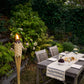 Natural woven torch with flame, outdoor dining setup.