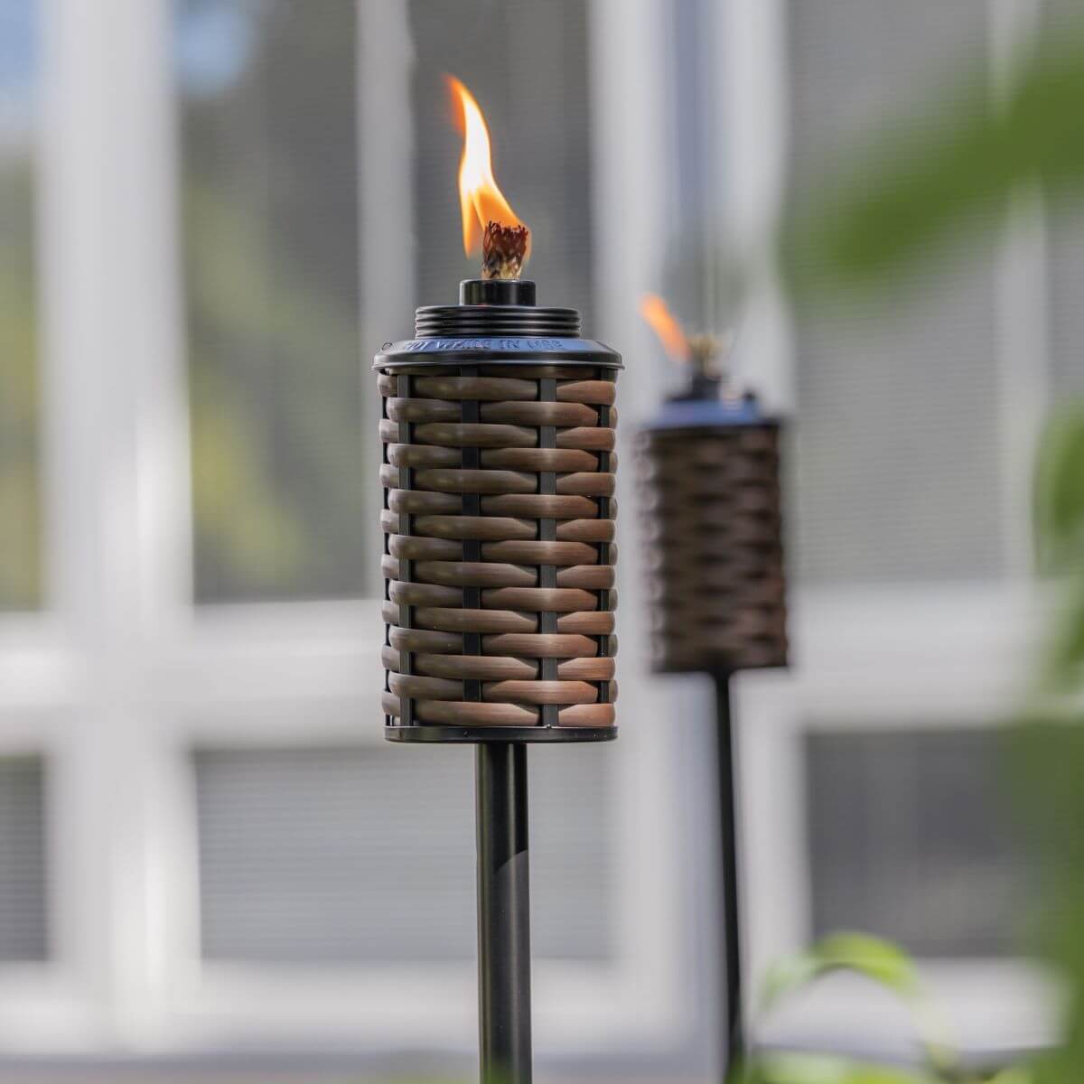 Brown woven torch with flame, outdoor decor.
