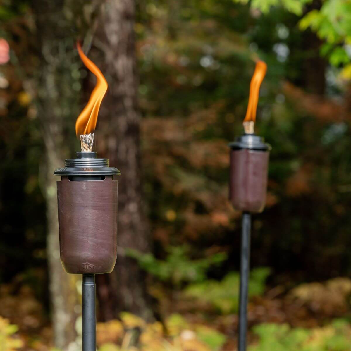 Brown Tiki torches with orange flames, outdoor setting.