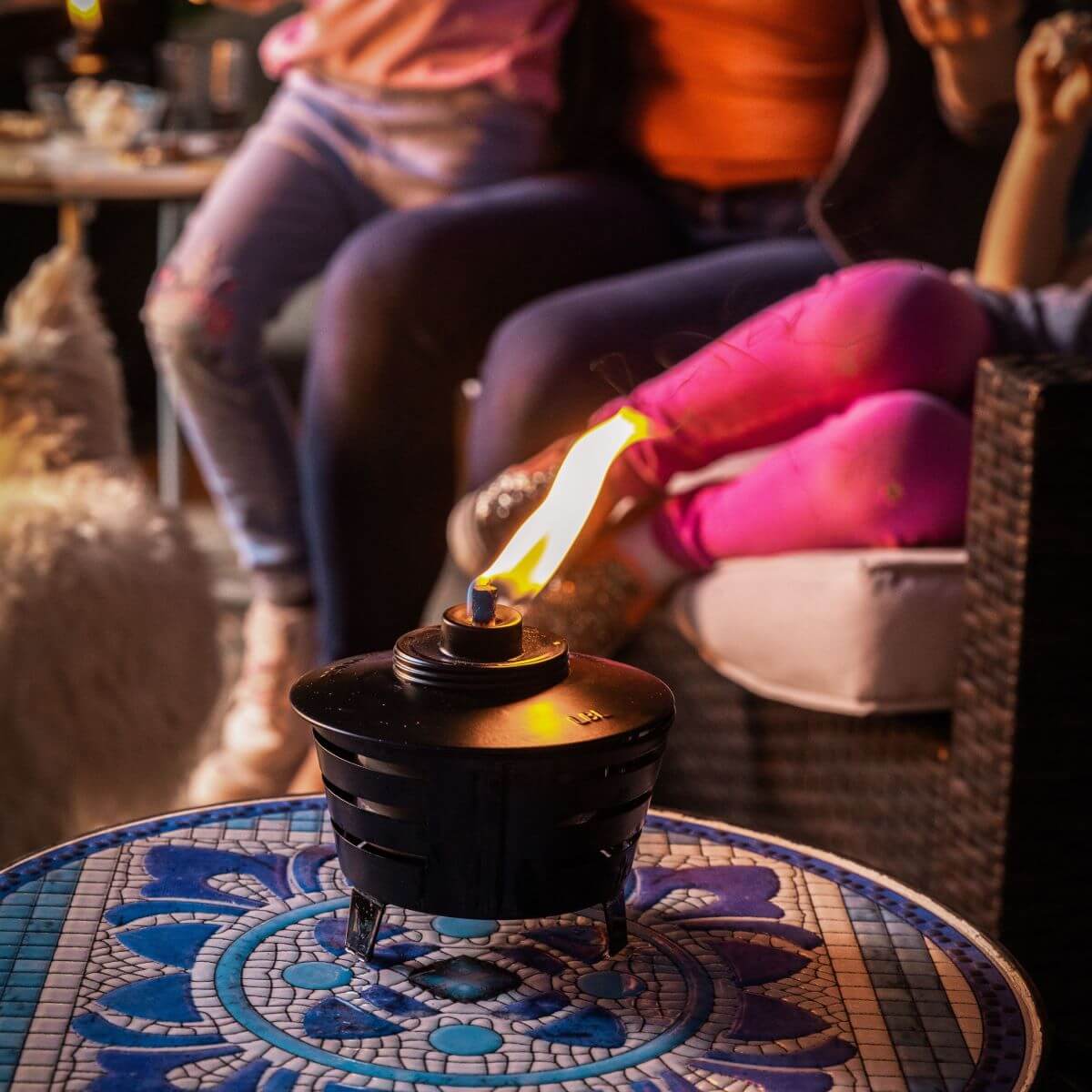 Black tabletop heater with flame, on patterned table.