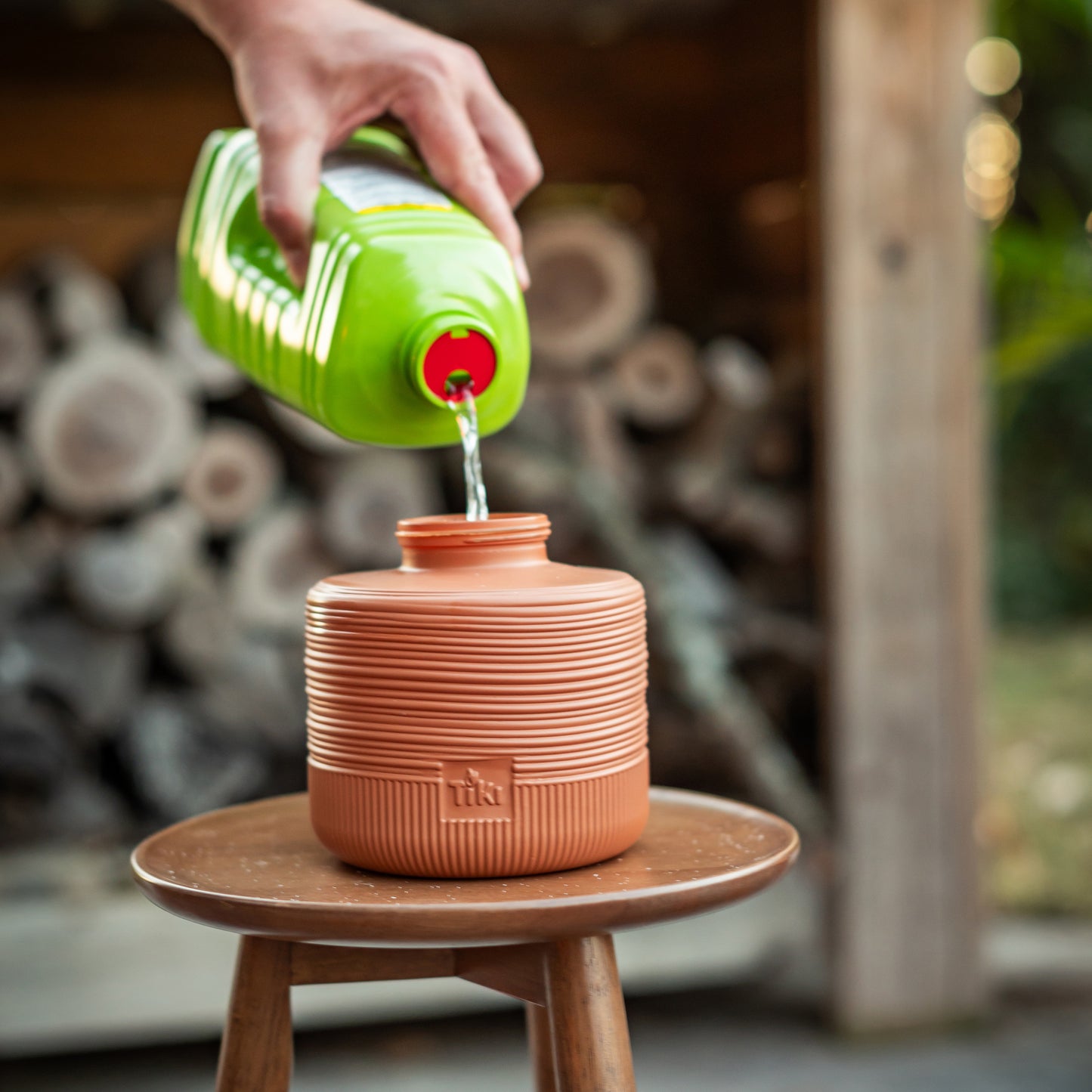 Orange TIKI terracotta tiki torch being filled with green fuel.
