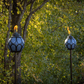 Blue decorative torches with flame, set outdoors near trees.