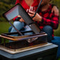 Portable folding grill with mesh lid and stand, outdoors.