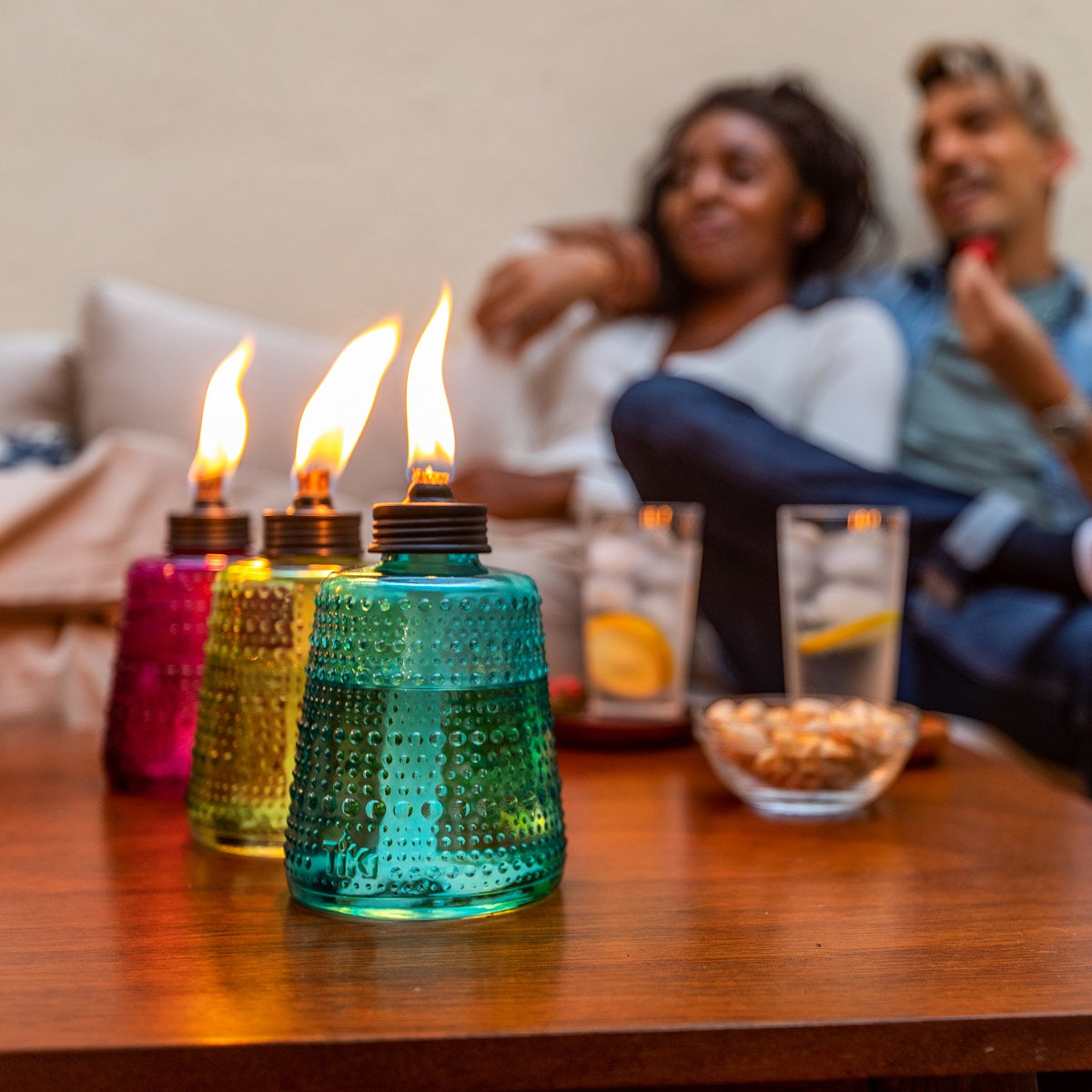 Colorful glass oil lamps with flames, set on a table.