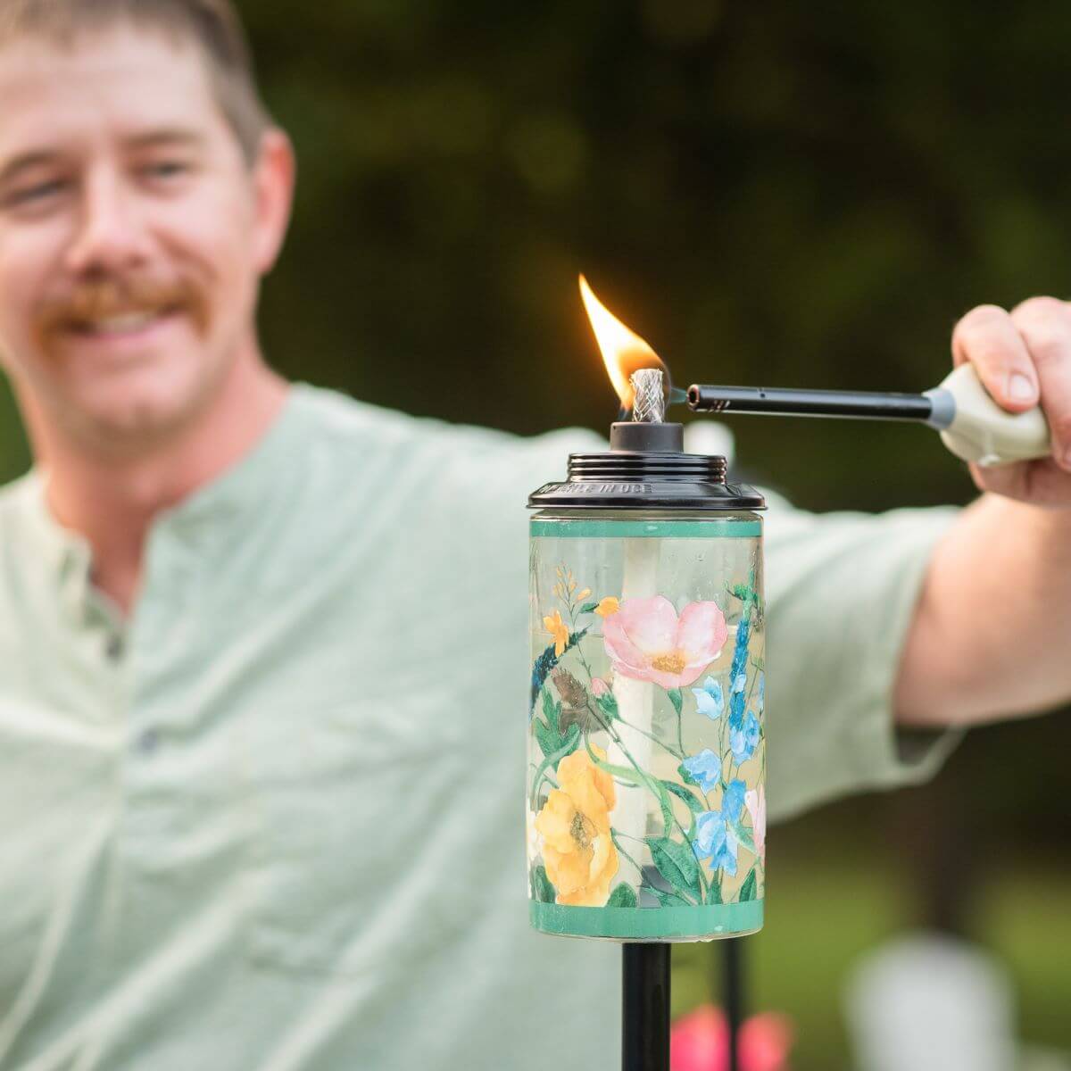 Colorful floral-patterned candle being lit with a lighter.