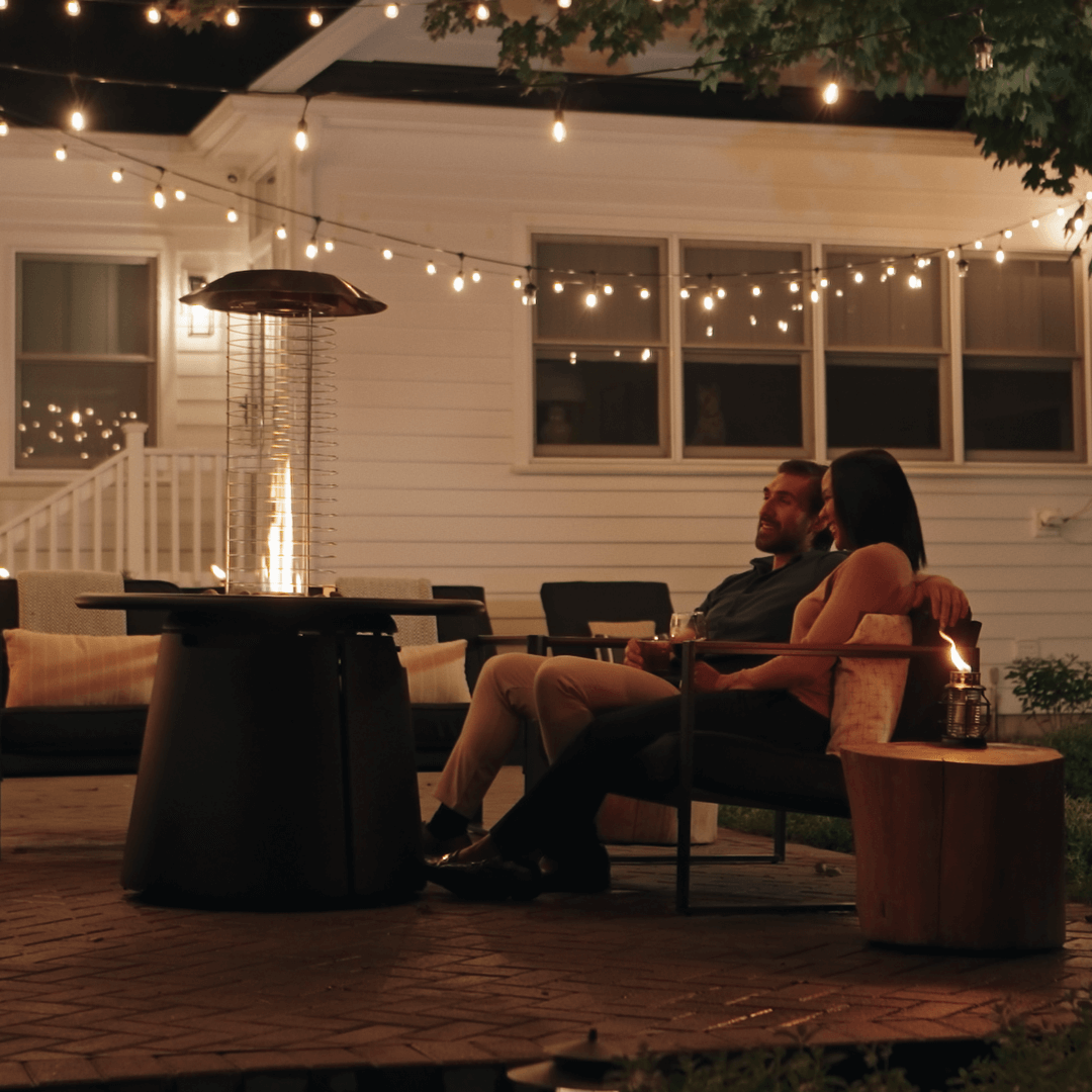 Outdoor patio heater with string lights and cozy seating area.