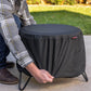 Black round table cover with brand tag, outdoor setting.
