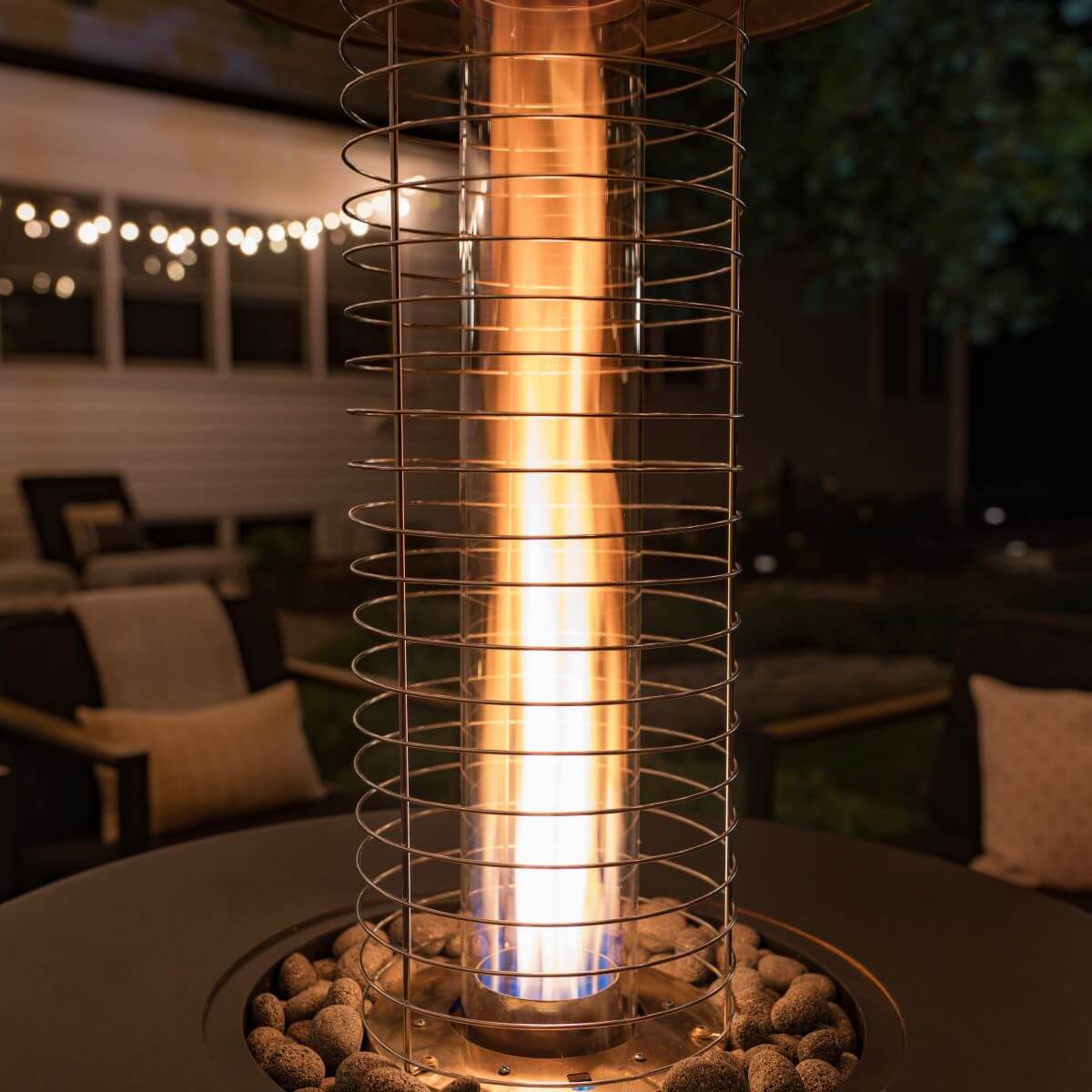 Gold spiral patio heater with glowing flame, outdoor setting.