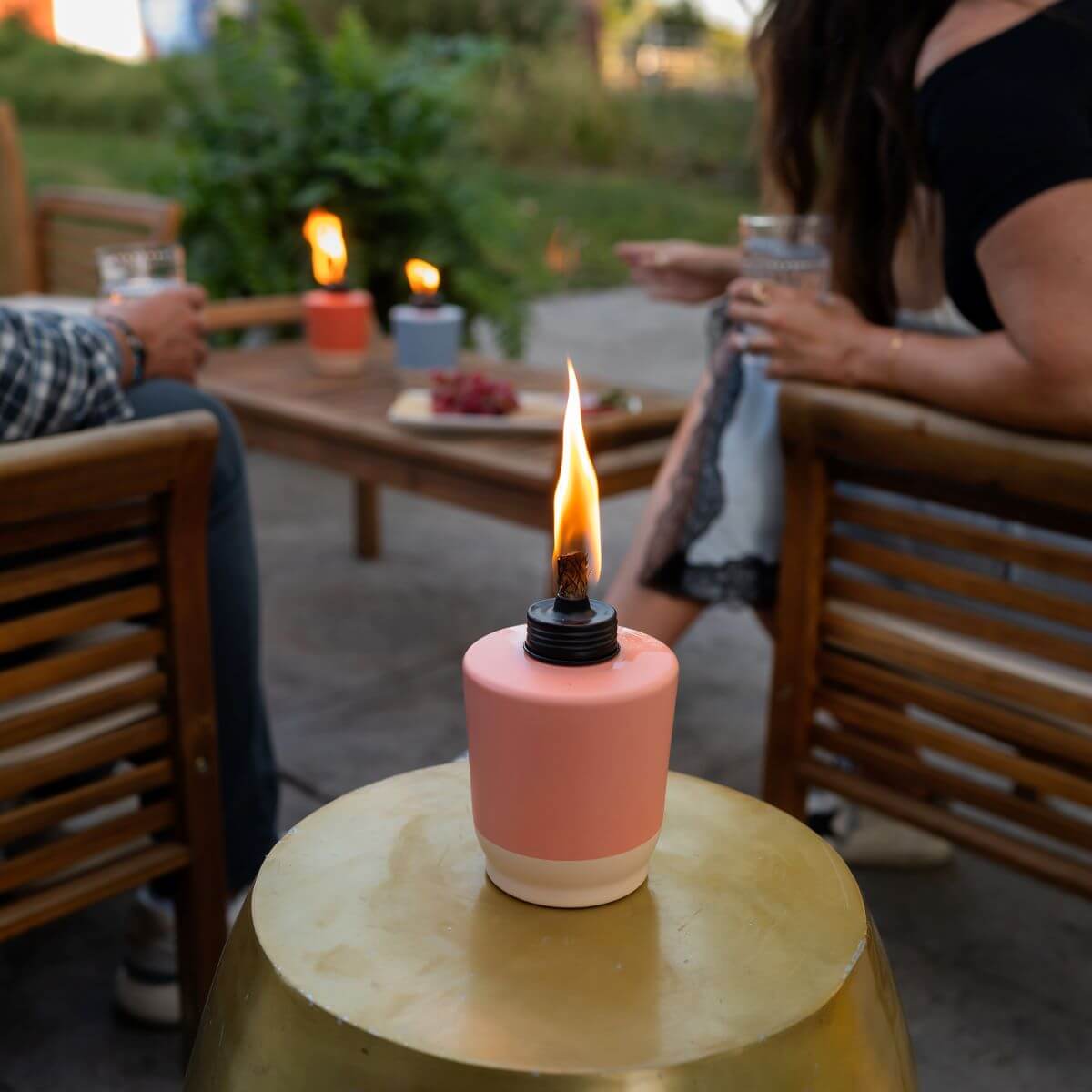 Pink tabletop torch with flame, outdoor setting.