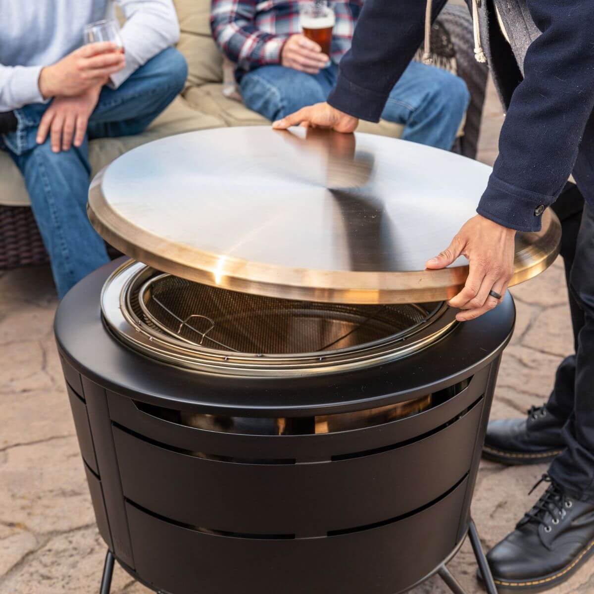 Black outdoor fire pit with lid, designed for gatherings.