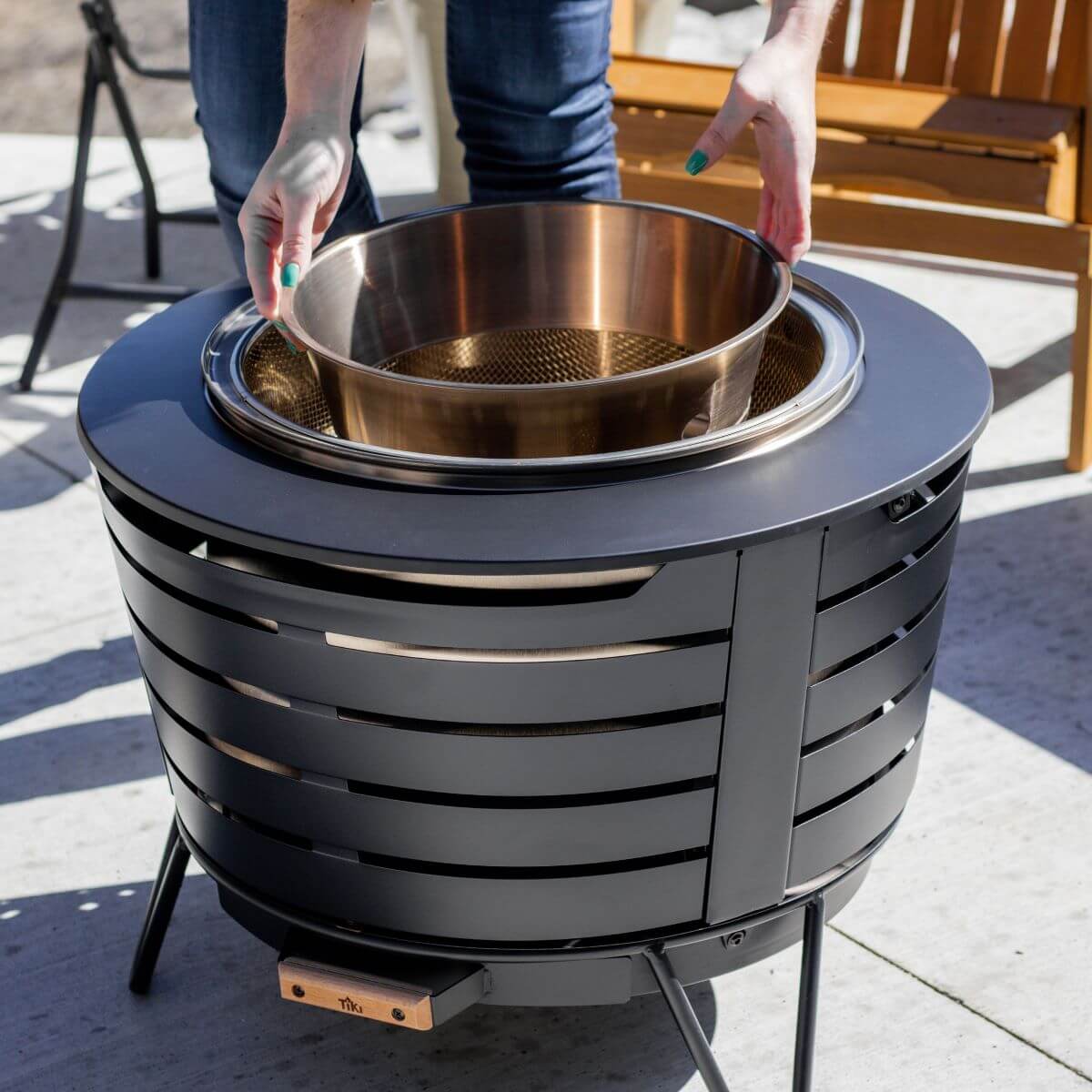 Dark gray outdoor fire pit with gold bowl and mesh insert.