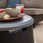 Gray round coffee table with modern design, featuring a dark base and a sleek surface.