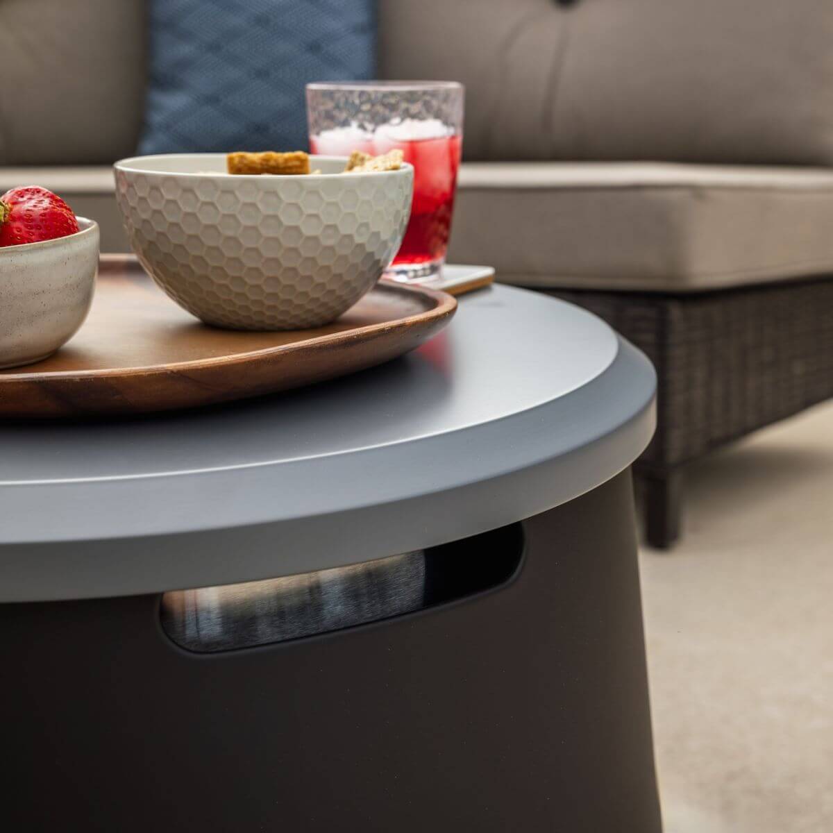 Gray round coffee table with modern design, featuring a dark base and a sleek surface.