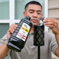 Black Tiki Brand Torch Fuel Citronella container being poured into a black torch.