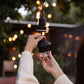 Black outdoor hanging light with glass diffuser, held in hand.