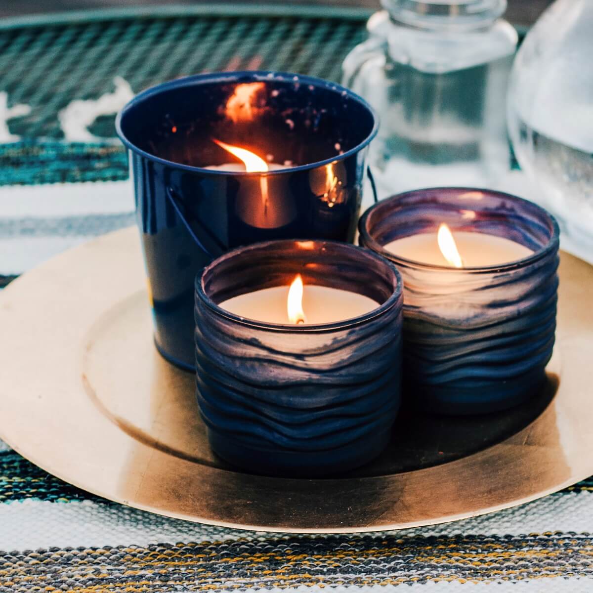 Three lit blue ceramic candles on a gold plate.