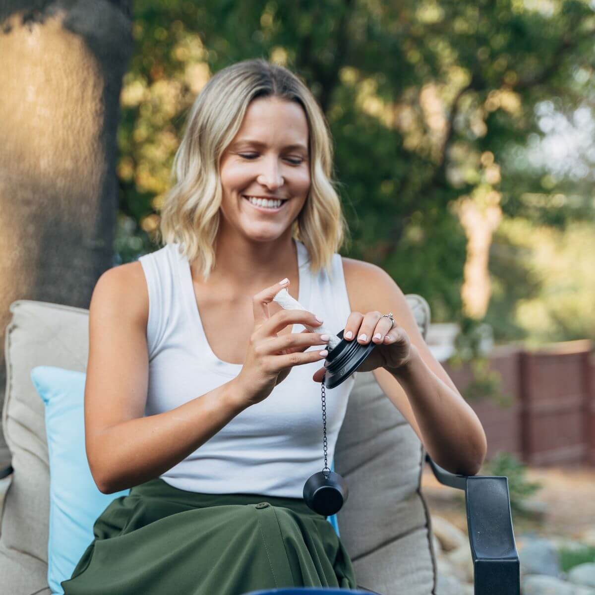 Black portable grinder with chain, held by person outdoors.