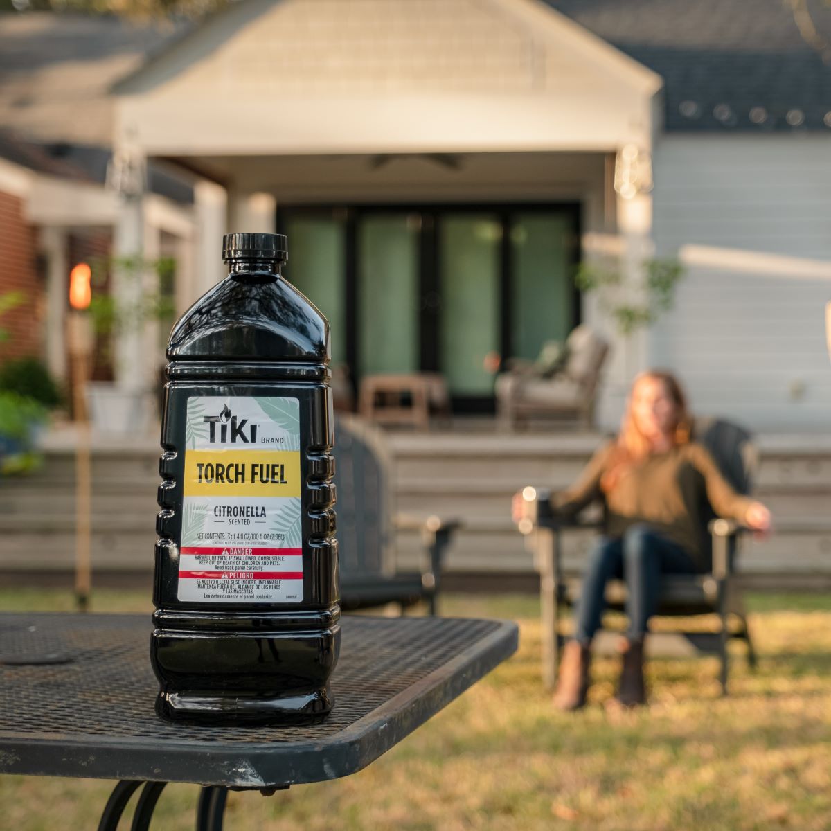 Black Tiki Brand Citronella Scented Torch Fuel bottle on outdoor table.