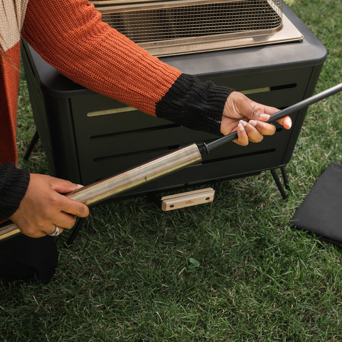 Black outdoor heater with adjustable handle, grass background.