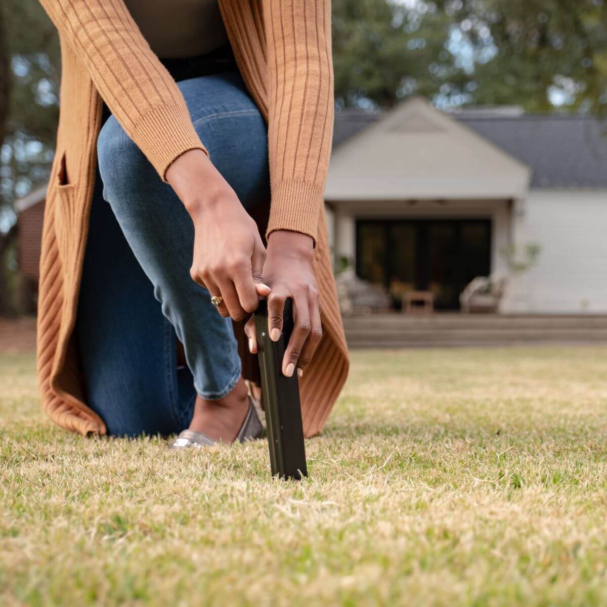 Black folding chair being held by person outdoors.