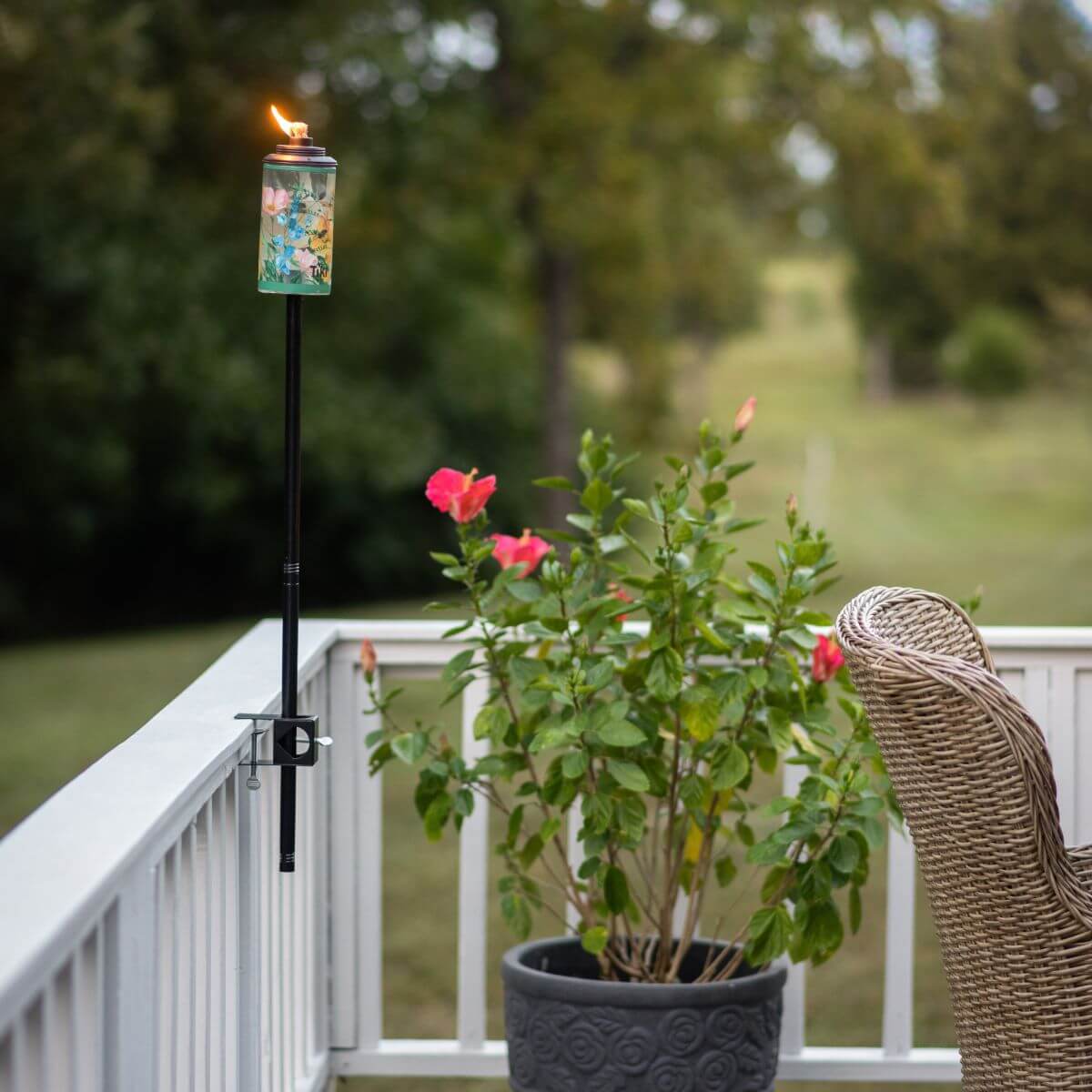 Black tiki torch with floral design, lit on outdoor patio.