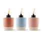 Three Tiki torches in coral, blue, and blush pink with cream bases and black tops.