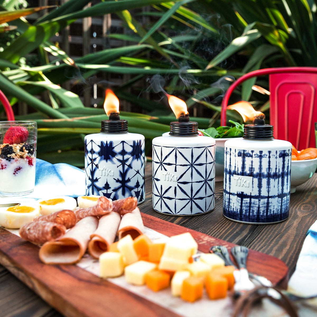 Blue and white patterned Tiki torches with flames, set outdoors with food.