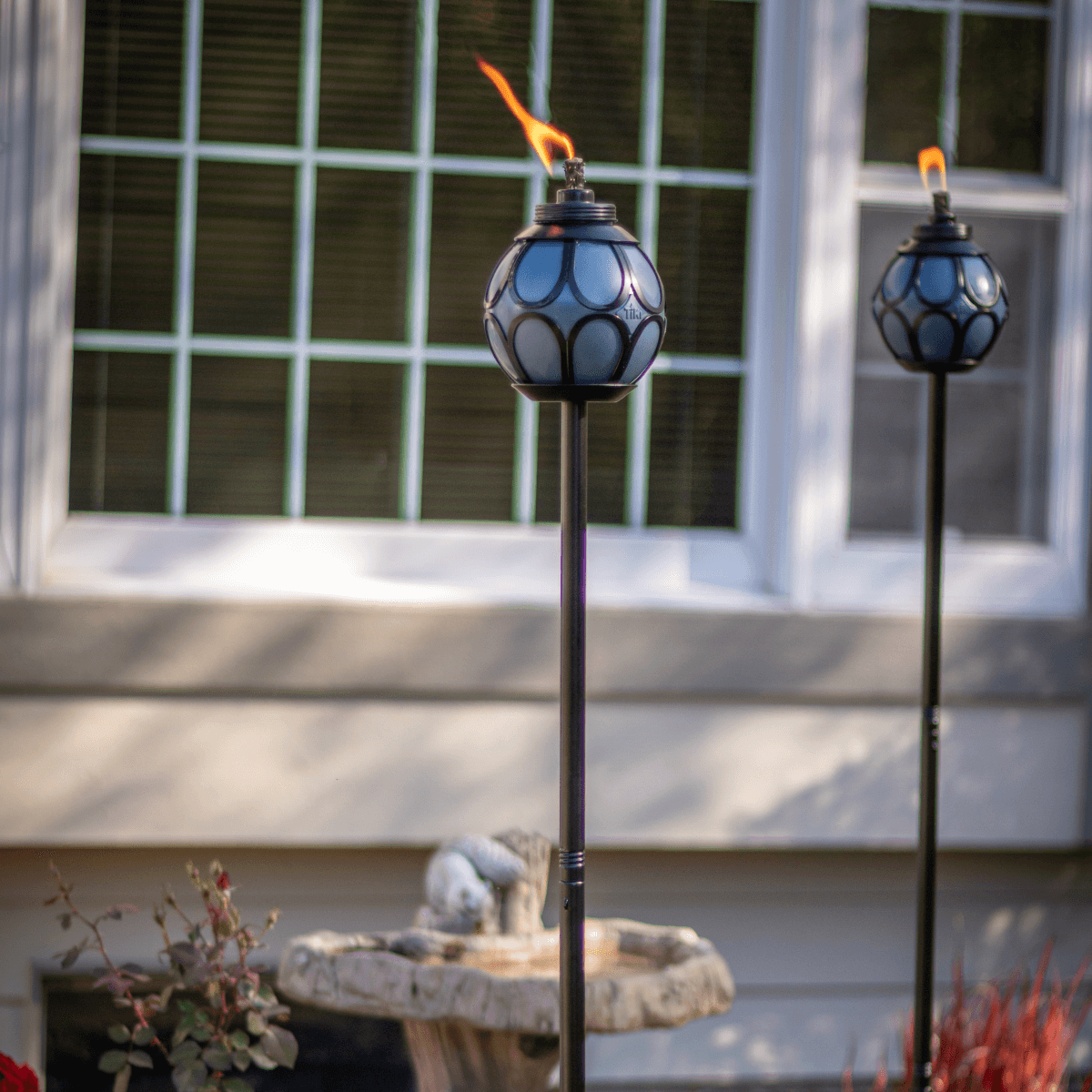 Blue decorative outdoor torches with flame, set on poles.