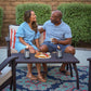 Blue patterned outdoor rug with wicker furniture and candles.