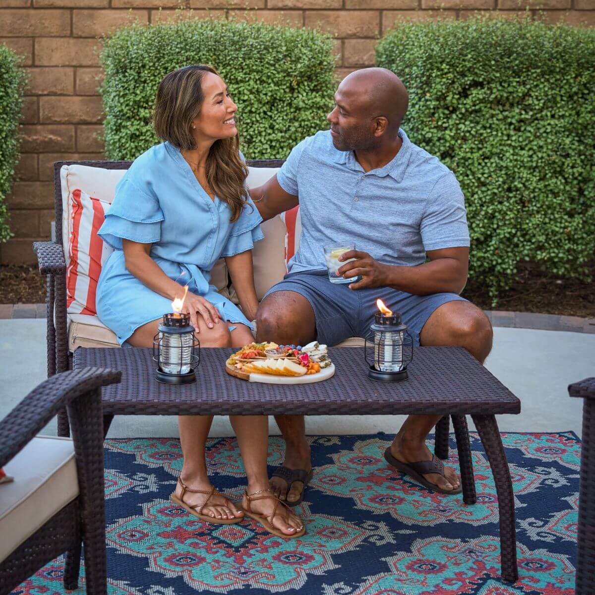 Blue patterned outdoor rug with wicker furniture and candles.