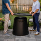 Black Tiki outdoor propane fire pit with lid being opened by two people.