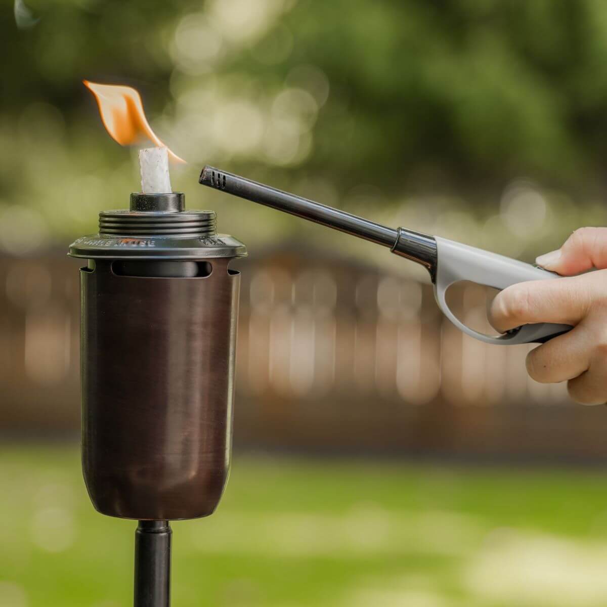 Black portable torch with flame, handheld igniter in use outdoors.