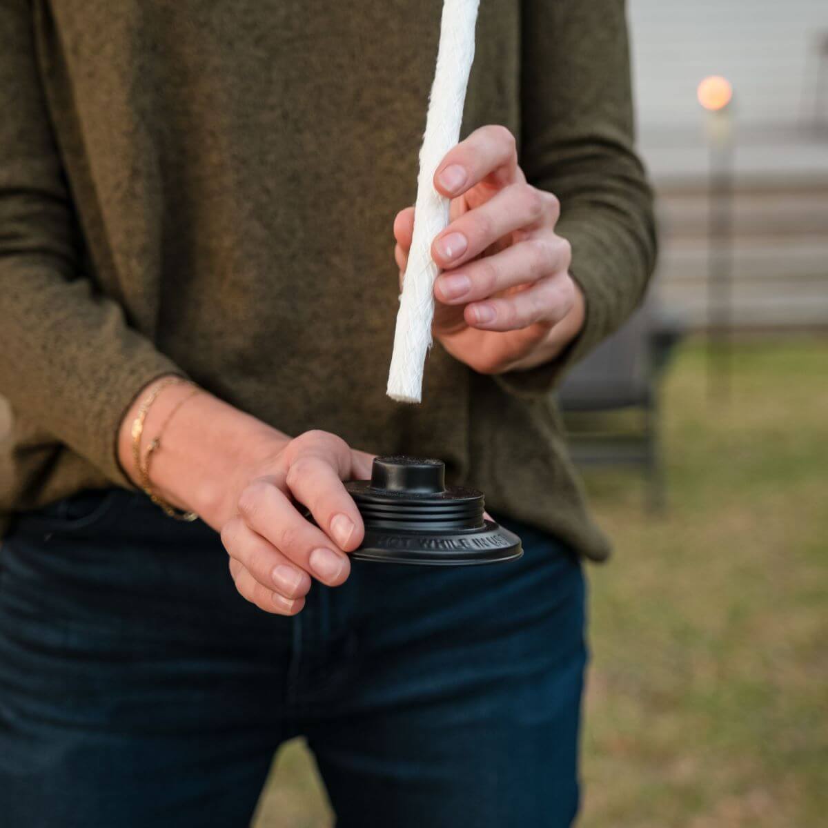 Person holding a white rope attached to a black spool, likely for outdoor or camping use.