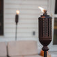Dark metal torch with flame, decorative cutouts, and stand.