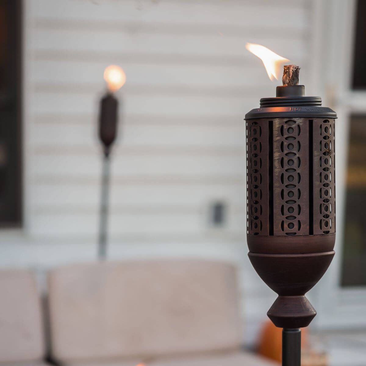 Dark metal torch with flame, decorative cutouts, and stand.