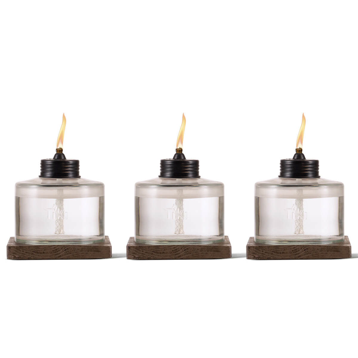 Clear glass Tiki torches with black tops and wooden bases, lit.