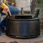 Black outdoor fire pit with perforated design and handle, modern style.