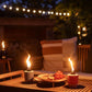 Candles and snacks on a wooden table outdoors at night.
