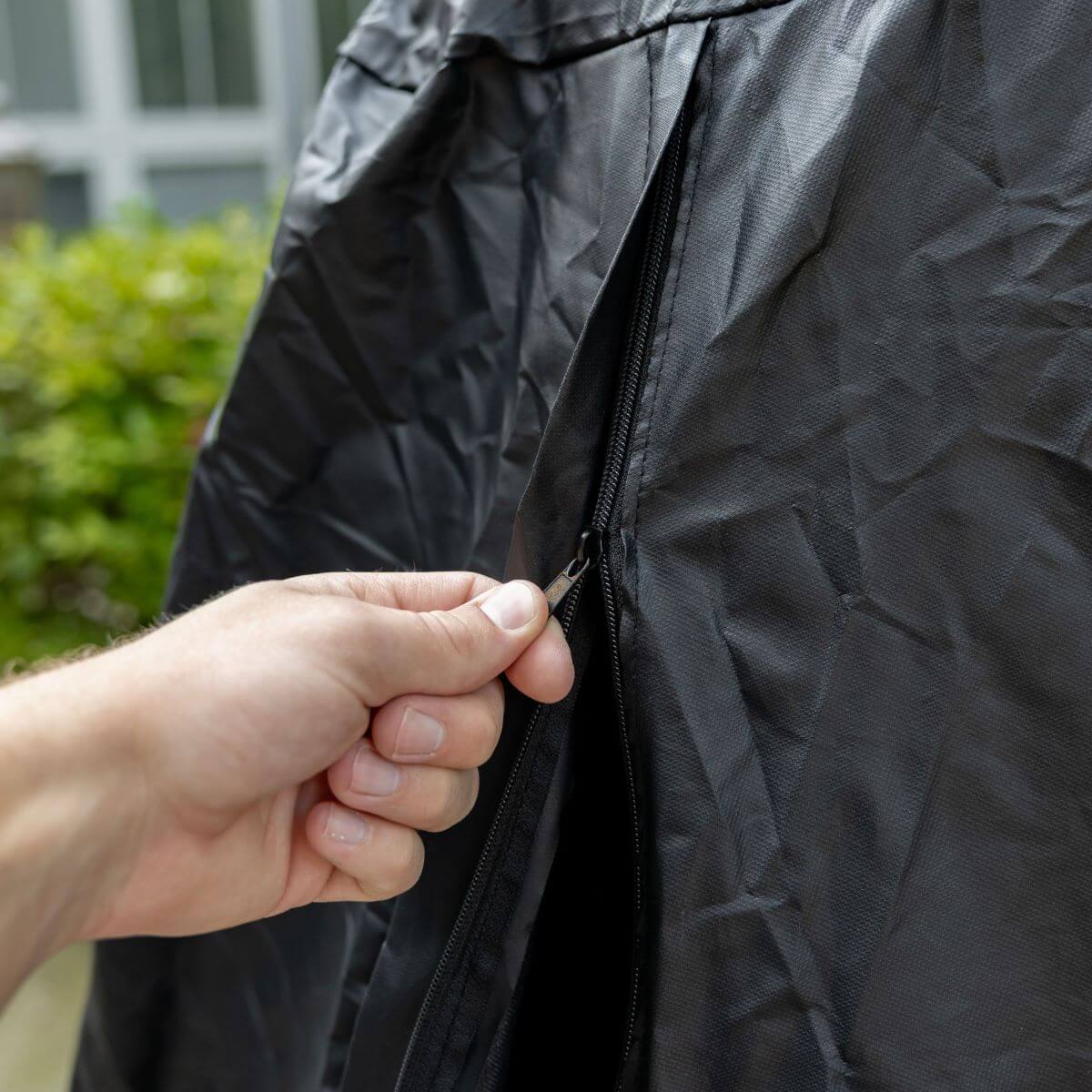 Black jacket zipper being pulled by hand.