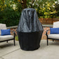 Black and gray outdoor grill cover on patio with chairs.