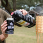 Black TIKI torch fuel bottle being poured into a canister.