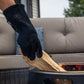 Black TIKI heat-resistant gloves for handling firewood near a fire pit.