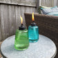 Green and blue glass TIKI torches on outdoor table.