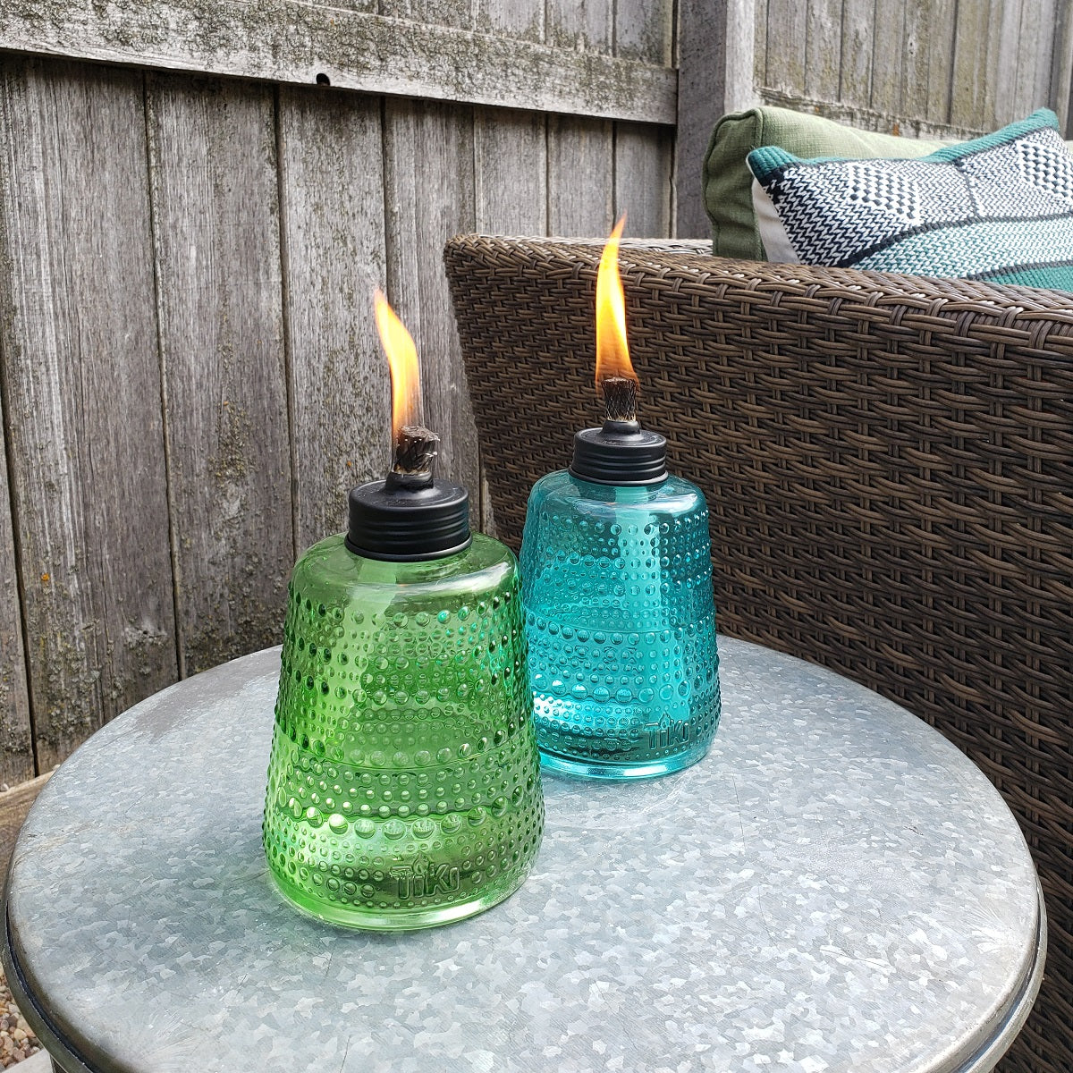 Green and blue glass TIKI torches on outdoor table.