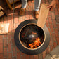 Modern black fire pit with flames, surrounded by red brick patio.