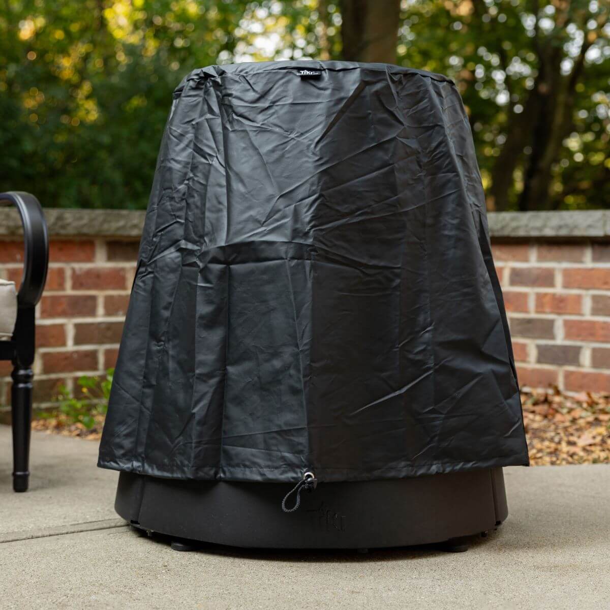 Black outdoor grill cover with drawstring closure, suitable for patio use.