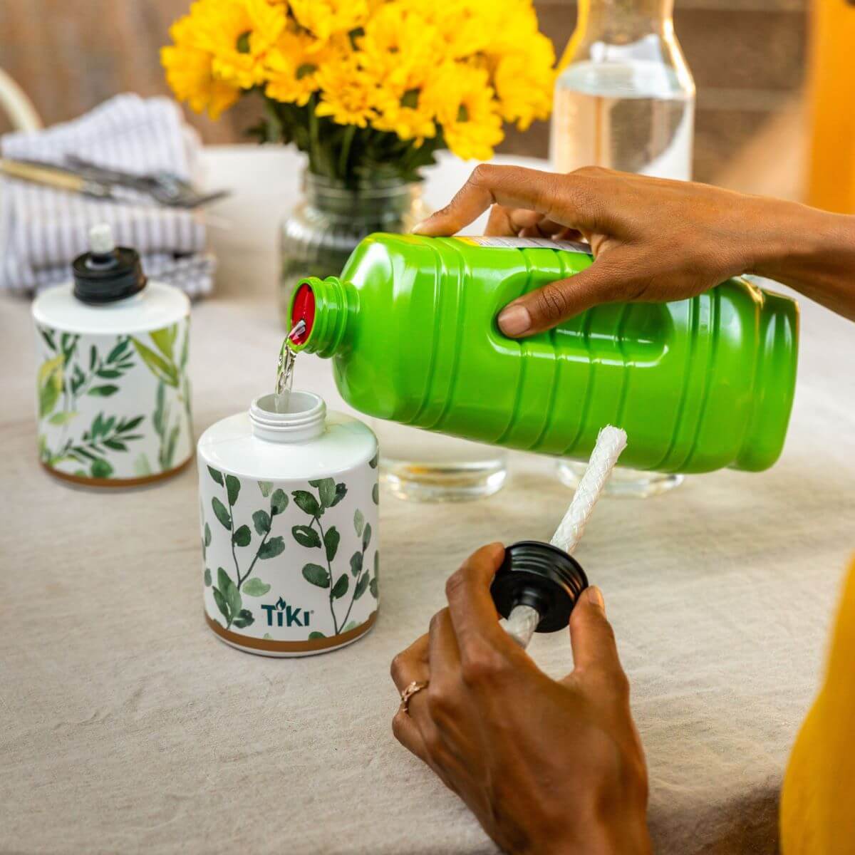 Green Tiki candle being filled with liquid from a green bottle.