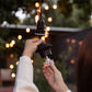Outdoor insect repellent diffuser being refilled, black hanging device with clear refill bottle, warm lights in background.