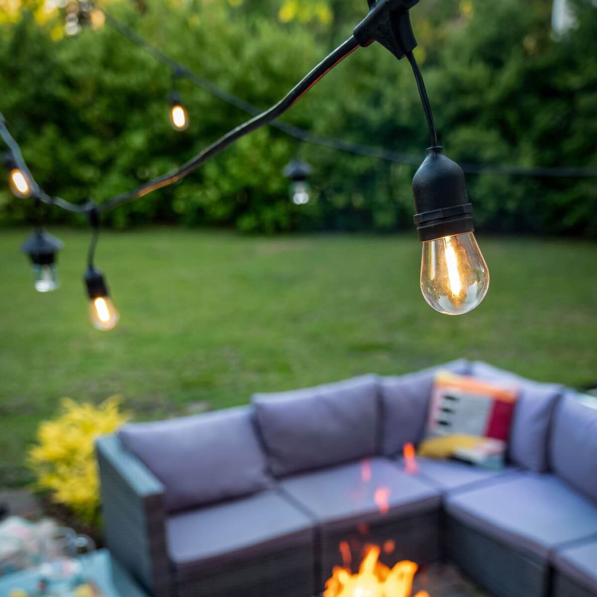 String of black outdoor Edison-style bulbs illuminating a patio setup.